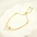 Detail eines verstellbaren 18K Goldperlenarmbands mit weißem Naturstein auf einer Muschel - Bergkristall-Stil (BR1694)