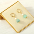 Dettaglio di orecchini a cerchio dorati con perla bianca e pietra verde chiaro su velluto - Blu Amazonite