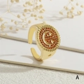 Detalle macro de un anillo de sonrisa dorado con piedras rojas y grabados de estrella - Estilo Sonriente Marrón Rojizo (RG0632-A)
