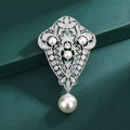 Broche plateado de estilo barroco con perlas y cristales sobre fondo verde oscuro - Y535