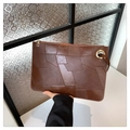 Détail de la pochette en cuir marron avec motifs géométriques et anneau métallique doré - café