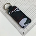 Close-up of camouflage neoprene lipstick holder with silver keychain on a grid scale - Dark Green Camouflage