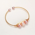 Macro detail of handmade 14K gold-plated wire-wrapped cuff with natural pink pearls - Gold Pink Purple Pearl Handmade Wrapped Style