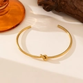 Brazalete abierto de acero inoxidable chapado en oro con un diseño de nudo central - Estilo Nudo (E223) / Color acero
