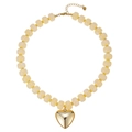 Dettaglio di una collana di perle in resina crema con un grande ciondolo a cuore dorato lucido. - Perla a Barile in Resina Stile Cuore (Stile-20)