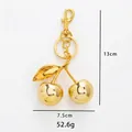 Portachiavi a ciliegia in metallo dorato, dimensioni 13x7,5 cm e peso 52,6 g su sfondo bianco - Ciliegia d'Oro