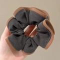 Minimalistische grijze stoffen scrunchie met bruine rand getoond in een lifestyle-opname - #1 Donkergrijze Stoffen Scrunchie Met Opgerolde Randen Circa 13 Cm