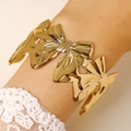 Detailed view of wide gold bow cuff bracelet with polished finish on model wrist - Bowknot Decoration Throughout Bangle (2508) / Gold