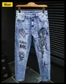 Detail der blauen Herrenjeans mit schwarzer Drachenstickerei und CALL ME-Aufdruck - EU 28 / Blau