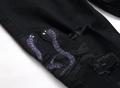 Detail der Cobra Stickerei und Distressed-Risse auf schwarzen Stretch-Streetwear-Jeans - EU 29 / Schwarz