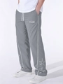 Dettaglio dei pantaloni sportivi grigi con ricamo a stella e etichetta sulla gamba - Grigio chiaro