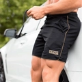 Short de sport homme avec cordon de serrage et liserés, porté par un mannequin - Noir/Or rose