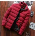 Dettaglio del piumino rosso trapuntato con tasche a zip su uno sfondo in legno scuro - Taglia M / Rosso