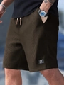 Detailed close-up of men's waffle knit shorts texture with drawstring and woven label - S / Dark Brown