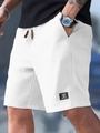 Detail of white waffle knit texture and black woven patch on men's casual shorts - S / White
