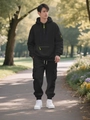 Male model in black hoodie and cargo jogger set with neon yellow zipper accents outdoors - Black