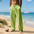 Men's loose light green linen pants with drawstring waist shown on a tropical beach - Fruit Green