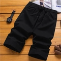 Schwarze Herren-Freizeitshorts mit elastischem Kordelzug auf Holzuntergrund gelegt - M / Schwarz
