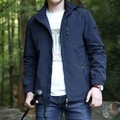 Detail van donkerblauw outdoorjack met capuchon, ritszakken en een rond merklogo op mouw - M / Donkerblauw