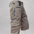 Close-up of tactical cargo shorts with multiple zipper pockets and a metal D-ring detail - Tan