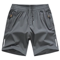 Dettaglio di pantaloncini sportivi grigio scuro con tasche a zip e tocchi arancio - M / Grigio