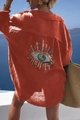 Detail of sequined evil eye embroidery on the back of a brick red crinkle fabric shirt - S / Orange