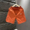 Detail of light orange quick-dry men's shorts with drawstring waist and white logo print - M / Orange Red
