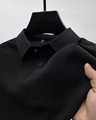 Detailed macro view of the 3D waffle texture fabric and three-button placket on black polo - Black