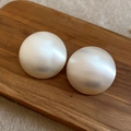 Gros plan sur des boucles d'oreilles ovales en métal brossé à effet nacré blanc mat - Style à tige d'argent / Argent