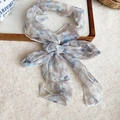Close-up of floral print mesh neck scarf tied in a bow on a linen background - Grey Floral