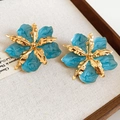 Detailed view of blue enamel flower earrings with gold metallic petal accents - Stud Earrings / Cyan