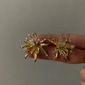 Detailed macro view of French luxury gold flower stud earrings with sparkling zircons. - Gold