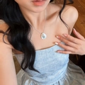 Close-up detail of a teardrop-shaped white shell necklace worn by a female model - Shell Style