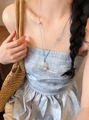 Detail of a vacation-style necklace with seashell and pearl pendant on blue cord - Pearl Style