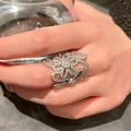 Close-up of a vintage-style hollow flower ring with sparkling zircon pavé on a hand. - Hollow Flower Style / Silver