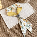 Close-up detail of the French tulip floral print scarf necklace with soft yellow fabric. - Yellow