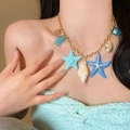 Close-up detail of a blue starfish and seashell necklace worn for a beach vacation look. - Gold-Blue