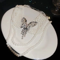 Détail macro d'un collier de perles françaises à plusieurs rangs avec un papillon - Six Rangs / Blanc Argenté