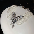 Détail du collier de perles à plusieurs rangs avec pendentif papillon en strass ajouré - Cinq rangées / Blanc