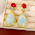 Detailed macro shot of vintage resin waterdrop earrings with colorful stones and gold frames - Blue