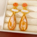Close-up of vintage resin drop earrings with marbled orange and amber textures in gold. - Brown