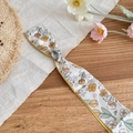 Detailed view of floral print silk scarf with textured silver metal slider clasp - Yellow Floral