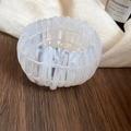 Close-up detail of a white marbled acrylic elastic bracelet on a rustic wooden surface. - White