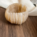 Close-up detail of beige marbled acrylic elastic bracelet on wooden surface - Light Coffee