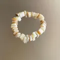 Detalle de cerca de cuentas de concha naturales en una pulsera de estilo bohemio - Estilo Cordón Elástico / Blanco puro