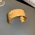 Dettaglio di un ampio bracciale a polsino dorato martellato con superficie testurizzata - Stile 15 - Oro