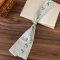 Vue détaillée d'un élégant foulard floral posé délicatement sur les pages d'un livre. - Floral/Tulipe Blanc (Collier)
