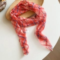 Close-up view of a lightweight retro plaid silk scarf draped on a natural wooden tray. - Red Plaid