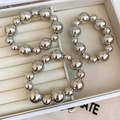 Macro view of three polished silver metallic bead bracelets in a white jewelry box - Three-Piece Set / 33# Bangle Silver