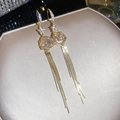 Close-up of 18k gold plated earrings with crystal flower pendants and long tassels. - Hook Style / Gold-White